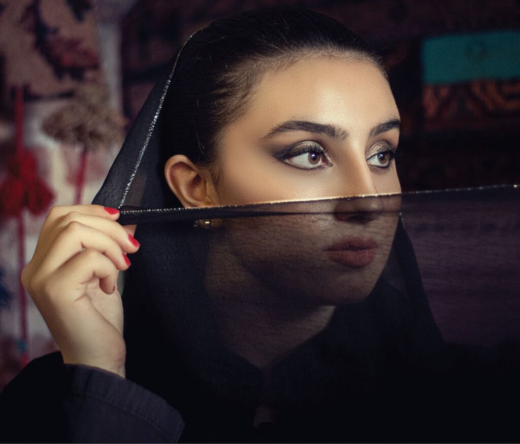 Stylish portrait of a woman wearing a sheer black veil with dramatic makeup. Captivating gaze.