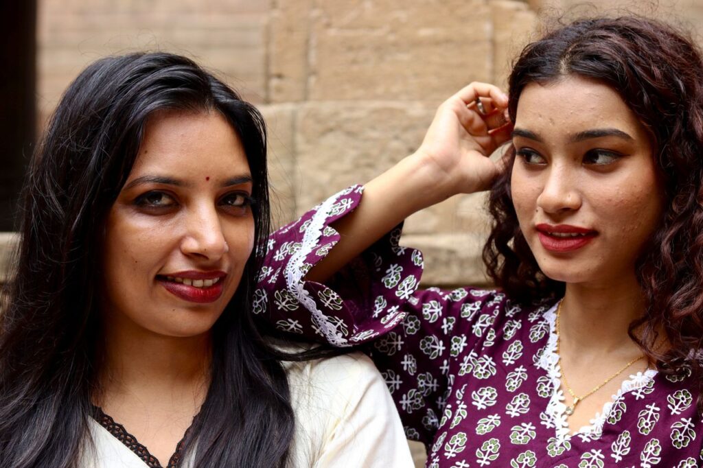 Close-up portrait of two women in vibrant traditional clothing outdoors.